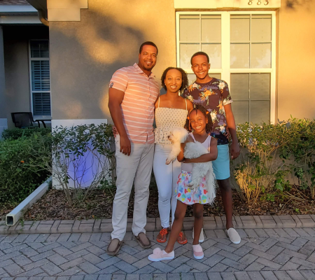 family-home-pros The family behind Home Pros Roofing and Contracting in Apopka, Florida—standing together in front of their home, smiling and holding their pet, symbolizing trust, care, and family values.